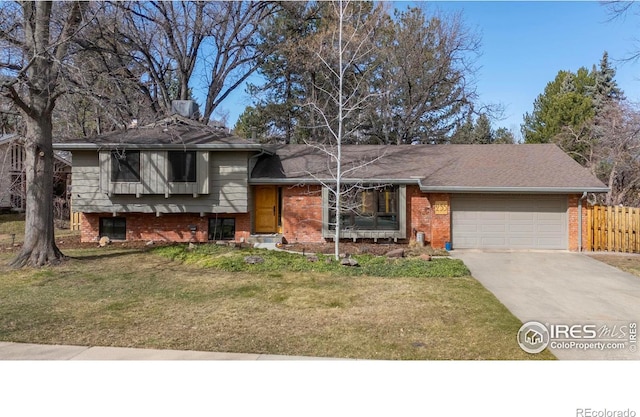 split level home featuring fence, an attached garage, a front lawn, concrete driveway, and brick siding