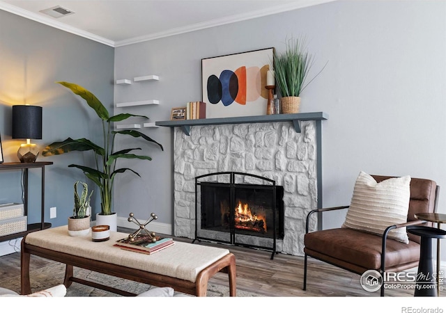 sitting room featuring wood finished floors, crown molding, a fireplace, and visible vents