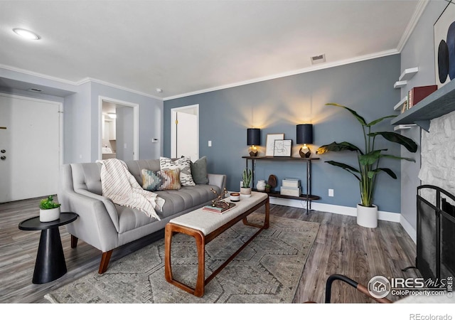 living room featuring wood finished floors, baseboards, visible vents, a fireplace, and crown molding