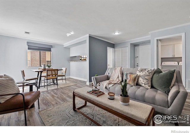 living area with visible vents, ornamental molding, separate washer and dryer, wood finished floors, and baseboards