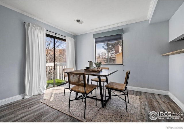 dining area with baseboards, visible vents, crown molding, and wood finished floors