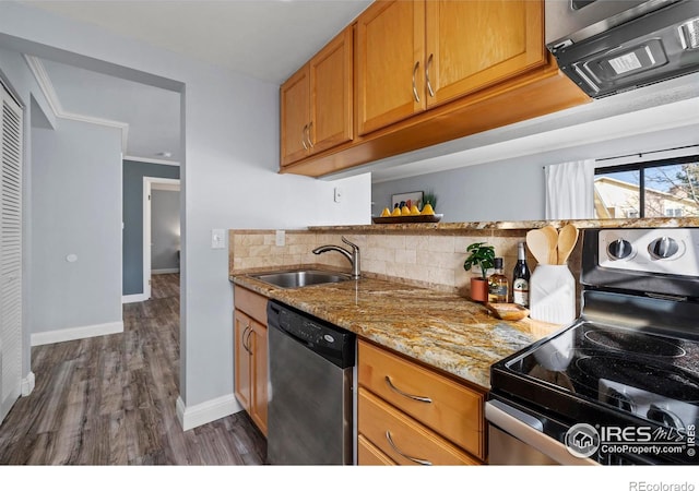 kitchen featuring tasteful backsplash, appliances with stainless steel finishes, dark wood-style flooring, light stone countertops, and a sink