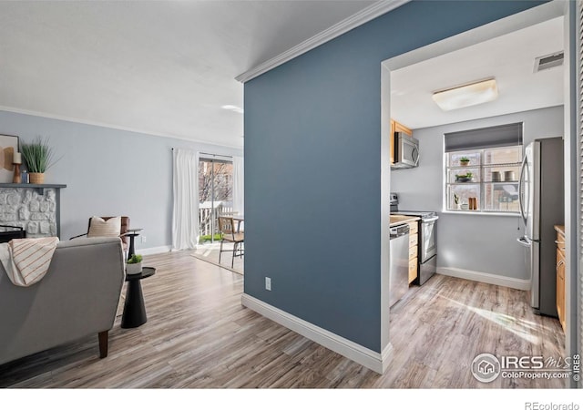 interior space with ornamental molding, light wood-style flooring, visible vents, and baseboards