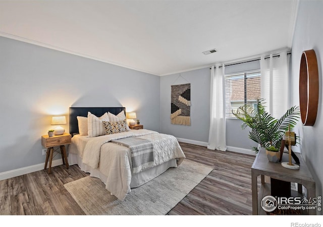 bedroom featuring wood finished floors, visible vents, and baseboards