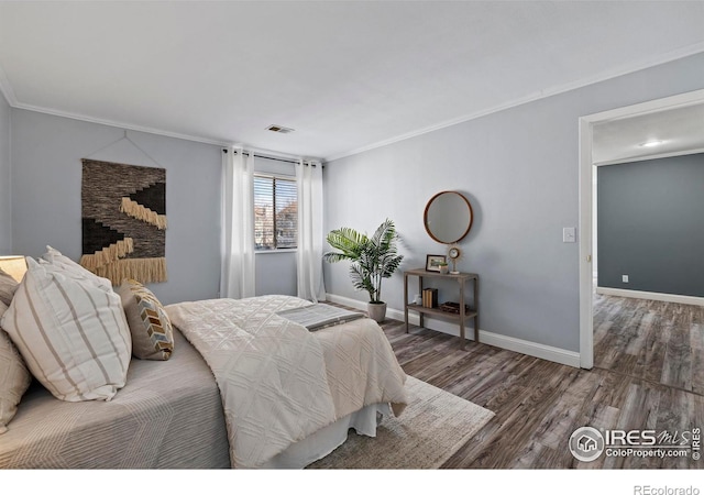 bedroom featuring ornamental molding, visible vents, baseboards, and wood finished floors