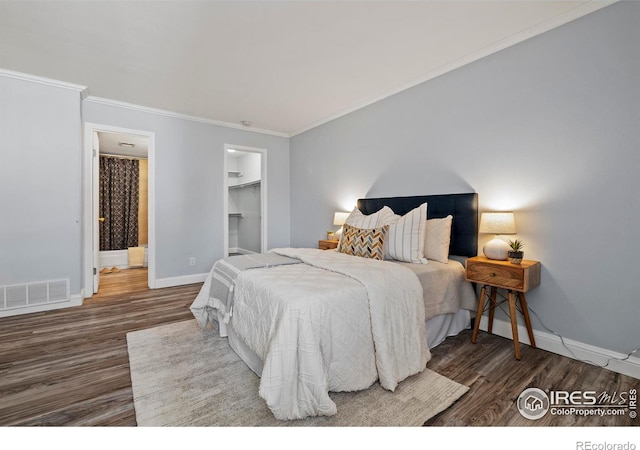 bedroom with crown molding, wood finished floors, visible vents, and baseboards