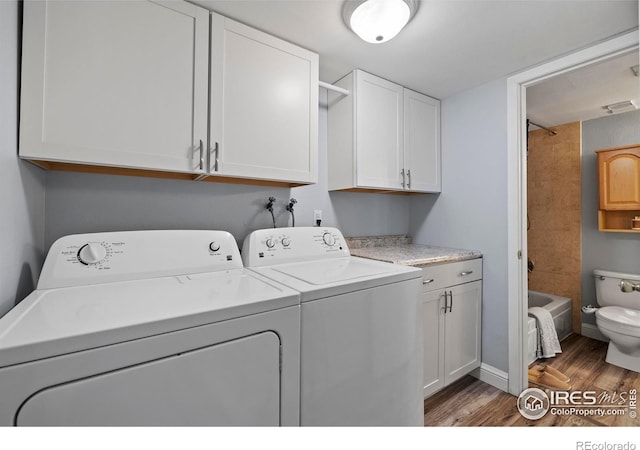 clothes washing area with laundry area, washing machine and clothes dryer, and wood finished floors