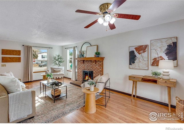 living room with a fireplace, a textured ceiling, baseboards, and wood finished floors