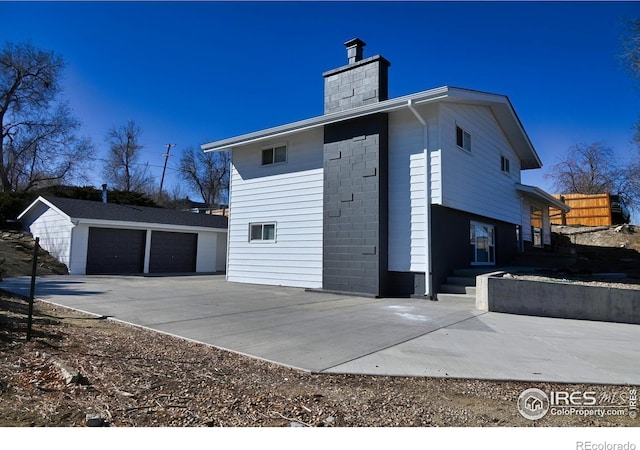 view of home's exterior with a garage, an outbuilding, and a chimney