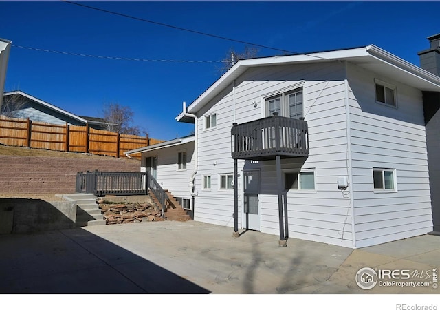 exterior space featuring a patio, a chimney, fence, and a balcony