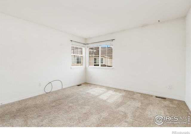 unfurnished room featuring carpet flooring, visible vents, and baseboards