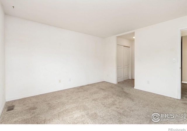 carpeted empty room featuring visible vents