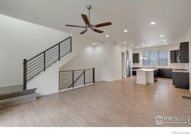 unfurnished living room featuring light wood finished floors, visible vents, a ceiling fan, a sink, and recessed lighting