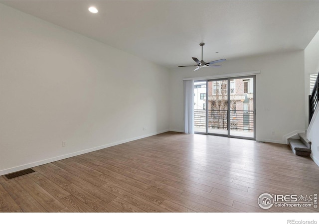 unfurnished living room featuring baseboards, visible vents, ceiling fan, wood finished floors, and stairs