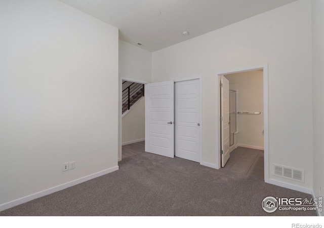 unfurnished bedroom featuring carpet floors, a closet, visible vents, ensuite bathroom, and baseboards