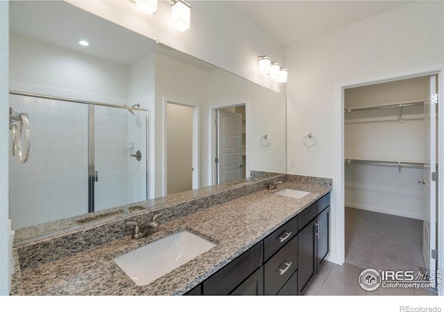 full bath with a spacious closet, double vanity, a sink, and a shower stall