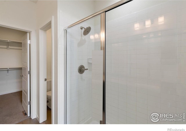 full bath with a spacious closet, a shower stall, and toilet