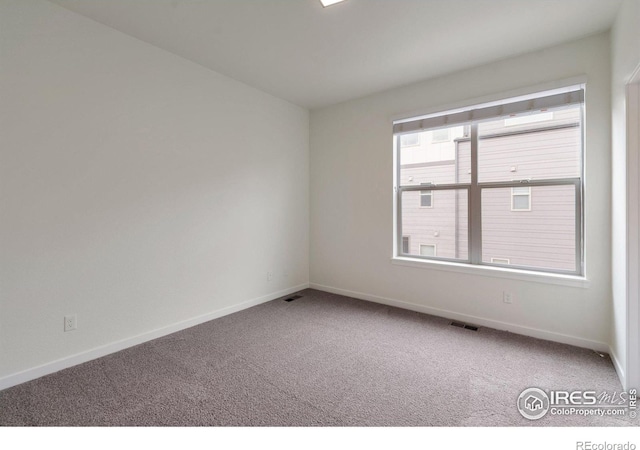 carpeted spare room with baseboards and visible vents