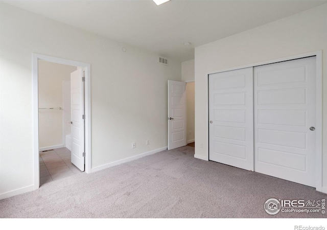 unfurnished bedroom featuring connected bathroom, carpet floors, visible vents, baseboards, and a closet