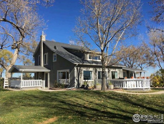 view of front of property with a chimney, a porch, and a front yard