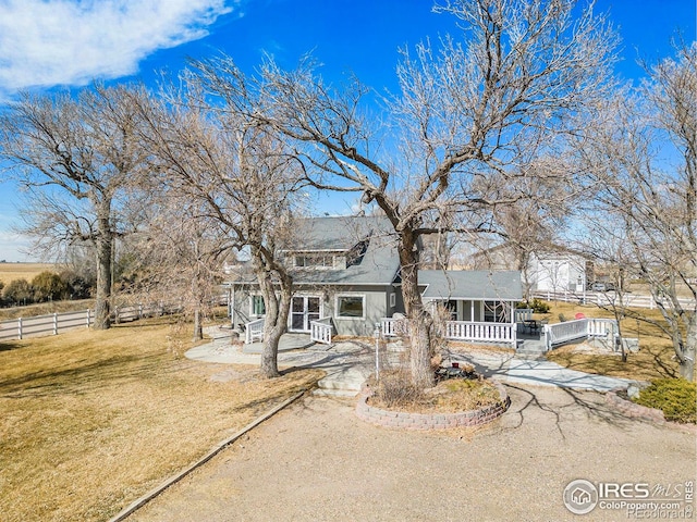 view of front of home featuring a front yard, covered porch, driveway, and fence