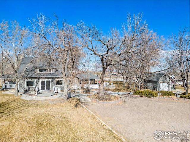 view of front facade featuring driveway, a porch, and a front yard