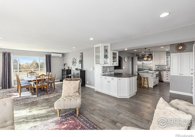 living room with recessed lighting, dark wood-style floors, baseboards, and a wall mounted AC