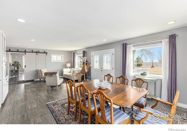 dining space with recessed lighting, a barn door, baseboards, and wood finished floors