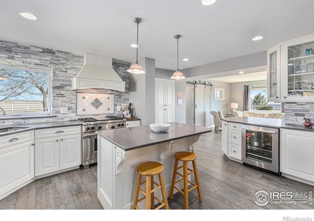 kitchen with wine cooler, custom exhaust hood, dark countertops, and high end range