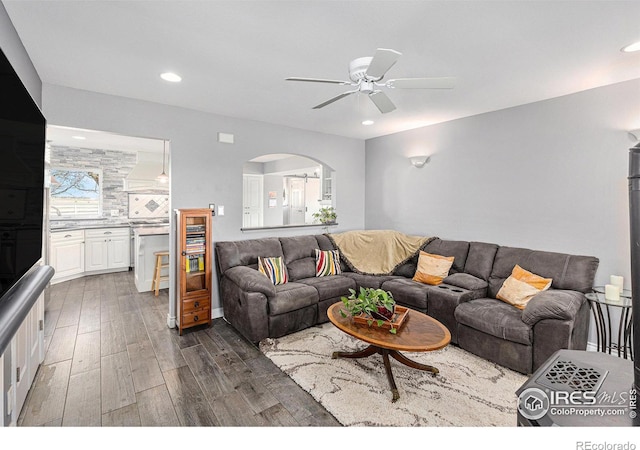 living room with dark wood finished floors, recessed lighting, arched walkways, and ceiling fan