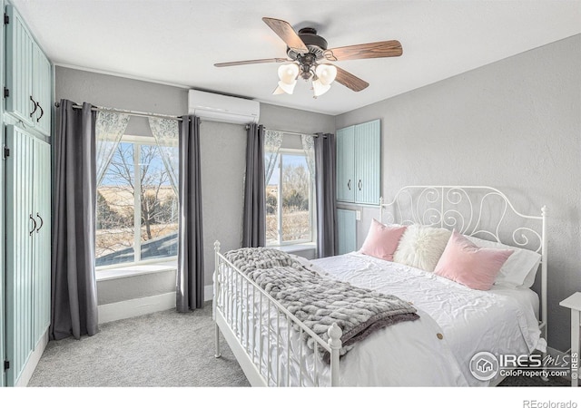 bedroom featuring an AC wall unit, a textured wall, baseboards, and light carpet