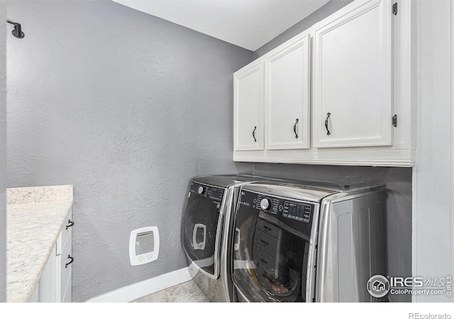 clothes washing area featuring cabinet space, independent washer and dryer, baseboards, and a textured wall