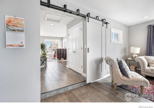 interior space featuring recessed lighting, baseboards, a barn door, and wood finished floors