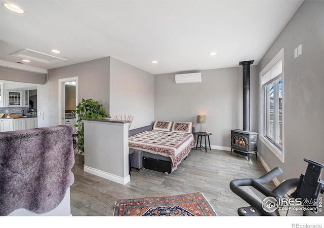 bedroom featuring recessed lighting, an AC wall unit, light wood-style flooring, and a wood stove