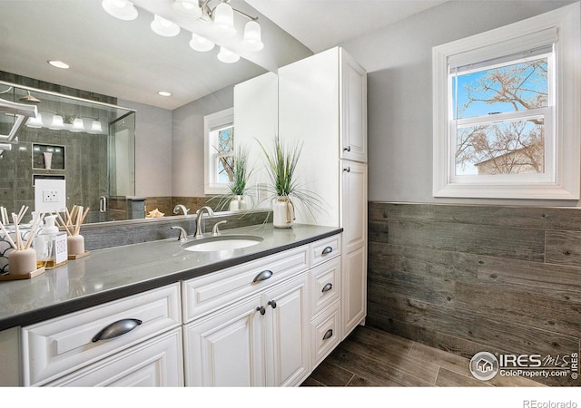 full bath with a wainscoted wall, wood finished floors, a stall shower, and vanity