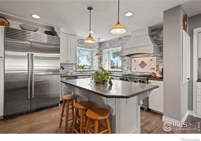 36340 County Road 49, Eaton, CO 80615 - kitchen with premium appliances, custom range hood, dark countertops, decorative backsplash, and recessed lighting
