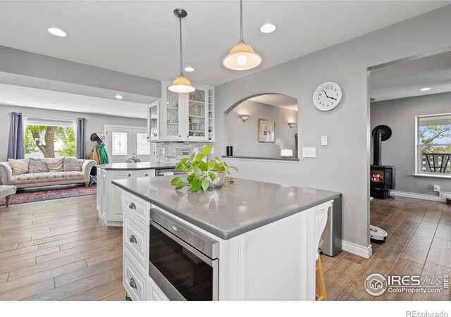 36340 County Road 49, Eaton, CO 80615 - kitchen featuring stainless steel microwave, open floor plan, light wood-style flooring, glass insert cabinets, and white cabinets