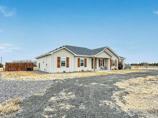 view of front of house with a shingled roof, fence, and board and batten siding