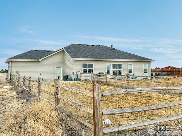 back of property with a shingled roof, fence, and central AC