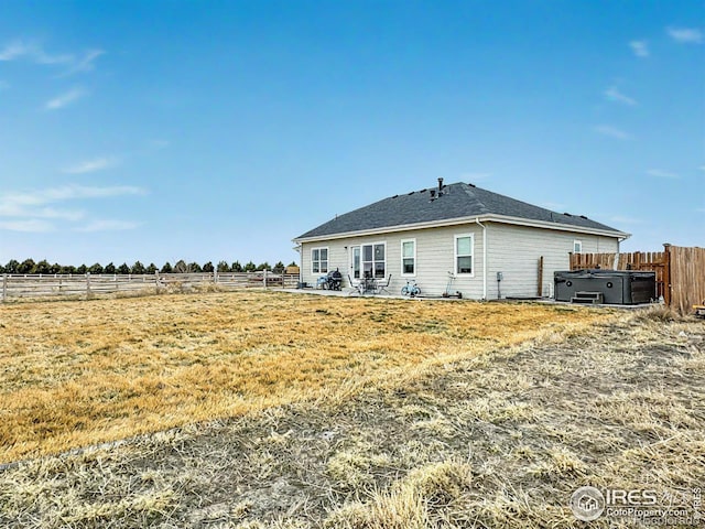 back of property with fence and a hot tub