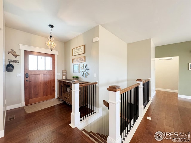 foyer entrance with a chandelier, visible vents, baseboards, and hardwood / wood-style flooring