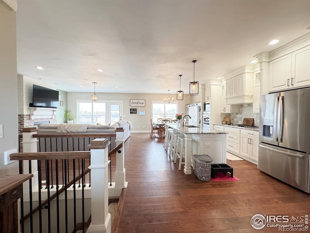 kitchen featuring decorative backsplash, open floor plan, dark wood-style flooring, stainless steel appliances, and a sink