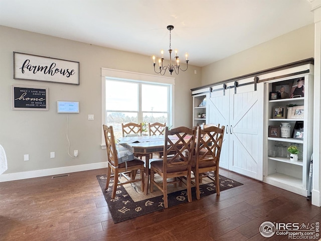 dining area with a barn door, visible vents, baseboards, dark wood finished floors, and a notable chandelier