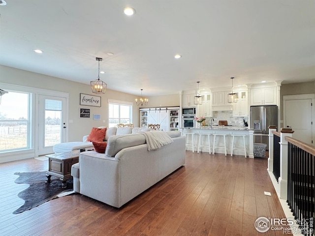 living room featuring a notable chandelier, dark wood-style flooring, and recessed lighting