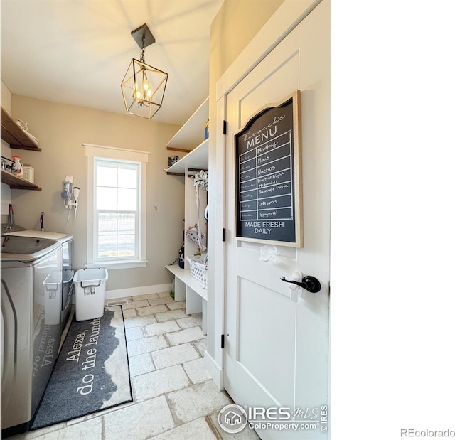 mudroom with baseboards, a notable chandelier, washing machine and clothes dryer, and stone tile floors