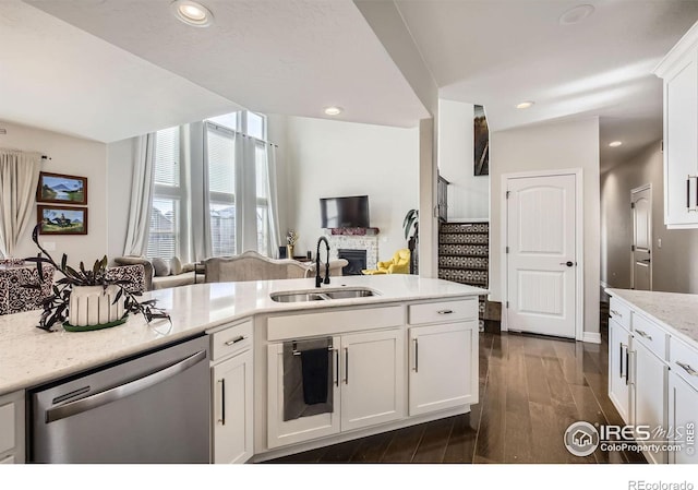 kitchen with a sink, white cabinetry, open floor plan, stainless steel dishwasher, and dark wood-style floors