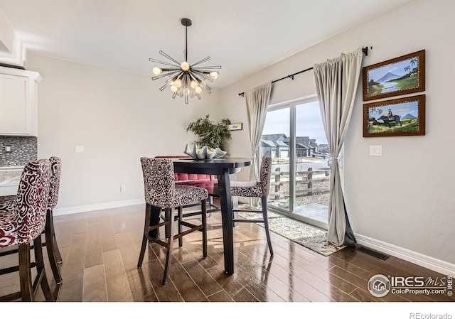 dining area featuring dark wood-style floors, visible vents, baseboards, and an inviting chandelier