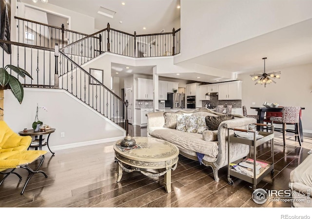 living room with an inviting chandelier, baseboards, stairway, and wood finished floors