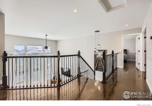 hallway featuring recessed lighting, baseboards, wood finished floors, and an upstairs landing