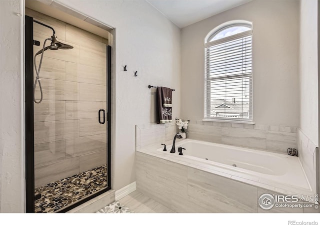 bathroom with a stall shower and a tub with jets